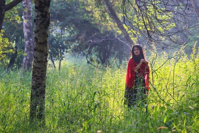 Woman standing on field in forest