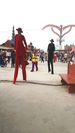 Group of people walking in city against sky