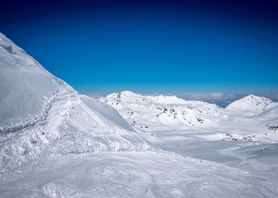 Scenic view of snowcapped mountains against clear blue sky