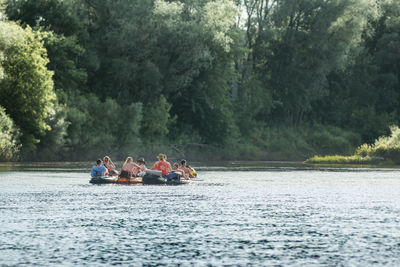 People in boat on river against trees