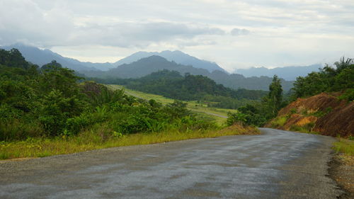 Road by mountains against sky
