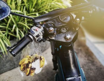 High angle view of bananas hanging in plastic bag on moped handlebar