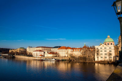 Buildings at waterfront against blue sky