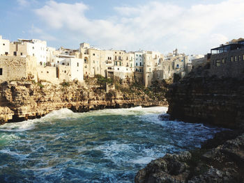 Buildings by sea against sky