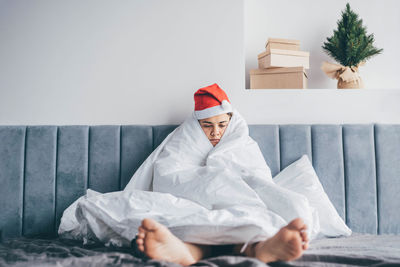 Low angle view of female friends sitting on bed at home