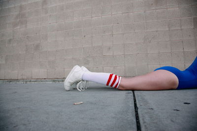 Low section of woman in gymnastics costume lying by wall