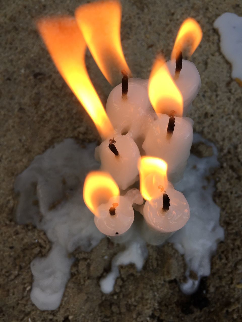 HIGH ANGLE VIEW OF LIT CANDLES ON FLOOR