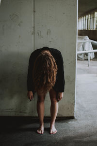 Rear view of woman standing against wall