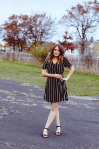 Portrait of smiling young woman standing against tree