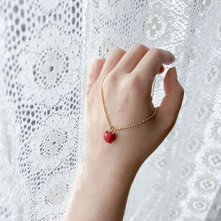 Cropped hand of woman holding red necklace.