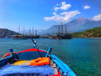 Sailboats moored in sea against blue sky