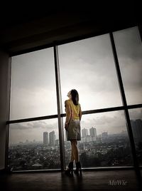 Full length of woman standing by window in city