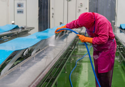 Worker use high pressure water spray cleaning conveyor belt after finishing daily job in slaughter.