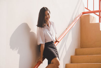 Woman holding umbrella on staircase at home