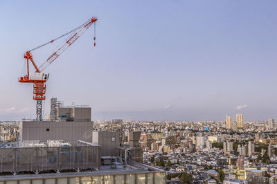 Cranes in city against sky