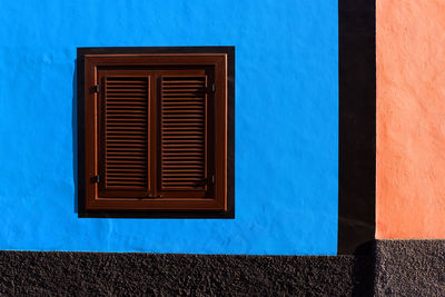 Close-up of closed window on blue wall