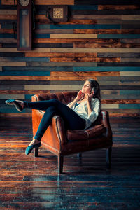 Full length of woman sitting on wooden floor