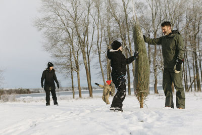 Father with son carrying christmas tree at winter