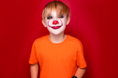 Portrait of boy standing against red background