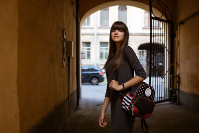 Cute young woman posing on the street , in a dress and a fitness bracelet on her arm