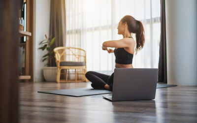 Young woman using laptop while sitting on hardwood floor at home