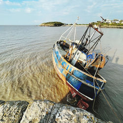 Fishing boats moored on sea against sky