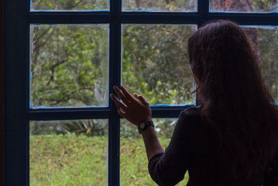 Rear view of woman looking through window