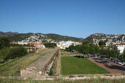 Scenic view of landscape and buildings against clear blue sky