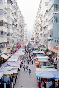 People on street amidst market stalls in city