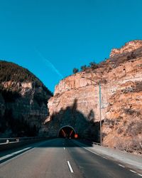 Car on road by mountain against blue sky