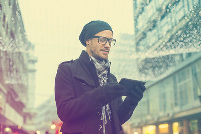 Man wearing warm clothing while using digital tablet in city