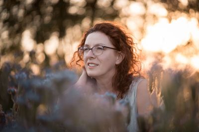 Mature woman standing between plants looking away