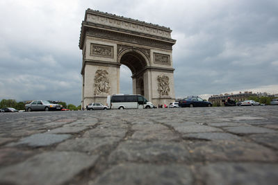 Low angle view of triumphal arch against cloudy sky