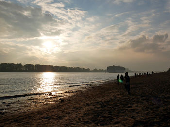 Tourists on beach against sky