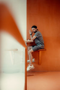 Side view of young man looking away against wall