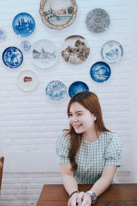 Portrait of smiling young woman standing against wall