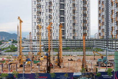 Construction site by buildings against sky in city