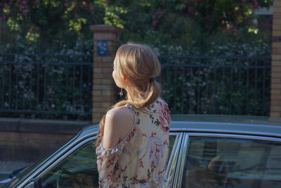 Rear view of woman standing by car in city