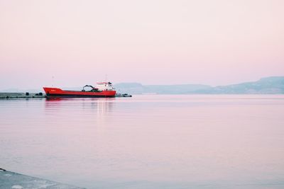 Fishing boat in sea against sky during sunset