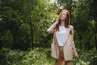 Young woman standing by plants in forest