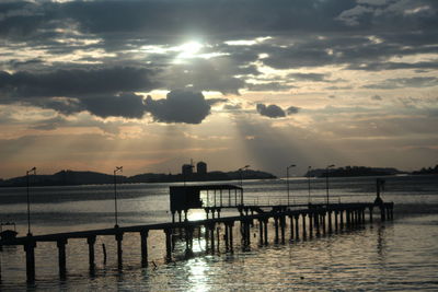 Pier over sea against sky during sunset