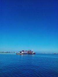 Ship sailing in sea against clear blue sky