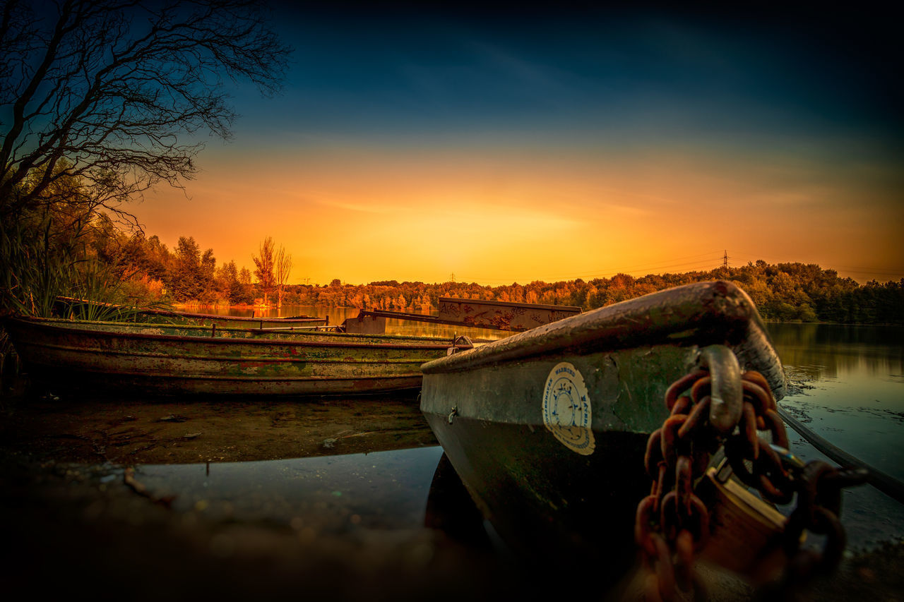 BOAT MOORED IN LAKE DURING SUNSET