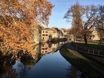 Buildings by river against sky