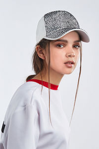 Portrait of young woman wearing hat against white background