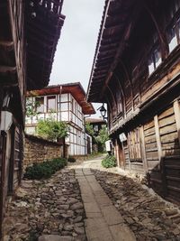 Footpath amidst old buildings against sky