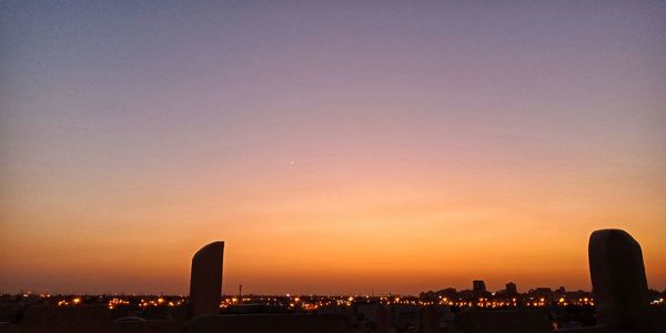 Illuminated buildings against clear sky at sunset