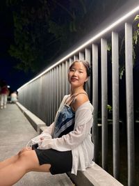 Young woman sitting on railing