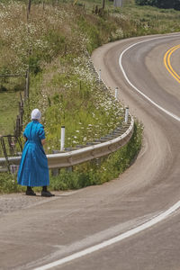 Rear view of a woman walking on country road