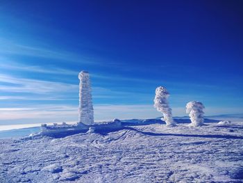 Built structure on snow covered land against blue sky